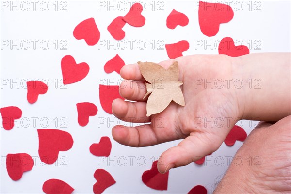 Paper butterfly and red paper hearts in hand