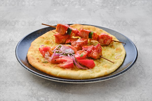 Shashlik served on tortilla with tomato and red onion
