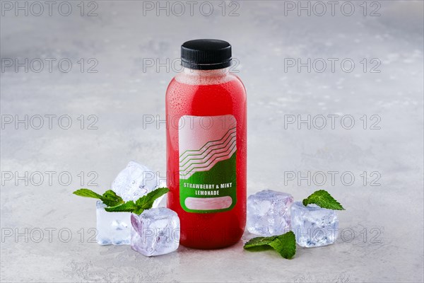 Small bottle with strawberry and mint ice lemonade on the table
