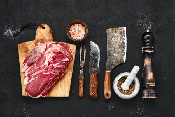 Overhead view of raw lamb shoulder without bone on wooden cutting board