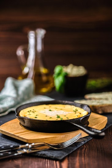 Omelette in cast iron skillet with bread and herbal butter