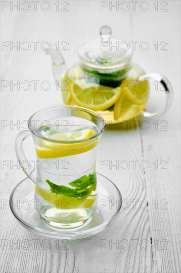 Antioxidant hot drink with lemon and mint in transparent tea pot and glass