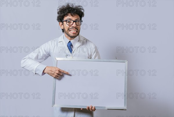 Amazed man in white coat pointing at a whiteboard. Male scientist in white coat holding and pointing at a blank whiteboard. Disheveled-haired man holding blank whiteboard