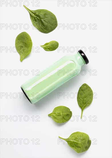 Flat lay juice bottle with spinach leaves