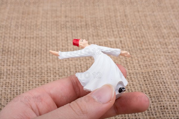 Hand holding a white color Sufi Dervish figurine in hand