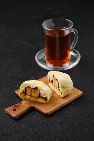 Sweet dessert mochi with banana and chocolate cut on half with fruit tea
