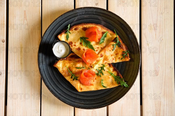 Top view of thin pancakes with salmon and sour cream