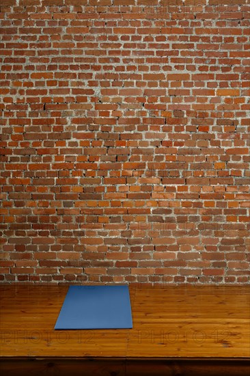 Gym mat on wooden podium with brick wall on background