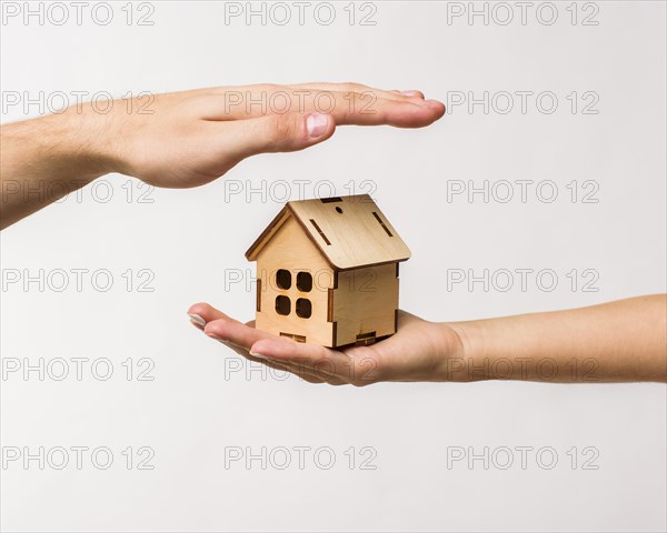 Hands protecting wooden cottage