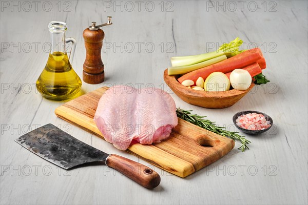 Raw fresh whole chicken breast with skin on carcas with ingredients for cooking