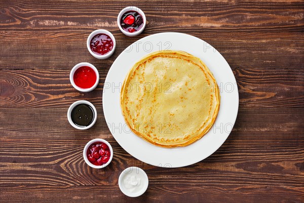 Top view of thin pancakes with assortment of jam and sauce