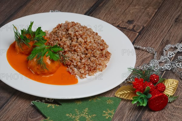 Buckwheat porridge and meatballs on wooden table near Cristmas tree toys