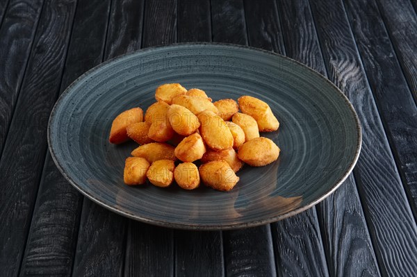 Portion of fried potato balls on dark wooden table