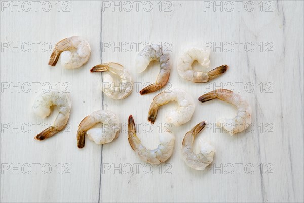 Peeled fresh raw white prawns on wooden background