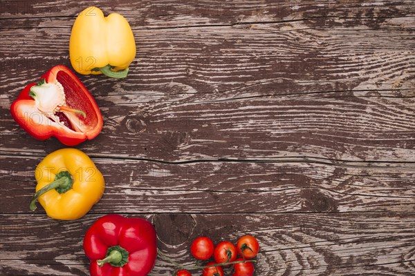 Red yellow bell peppers cherry tomatoes wooden desk