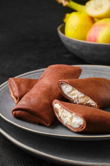 Closeup view of thin chocolate pancakes stuffed with curd