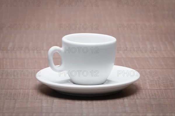 Clean and empty ceramic cup for espresso with saucer on wooden table