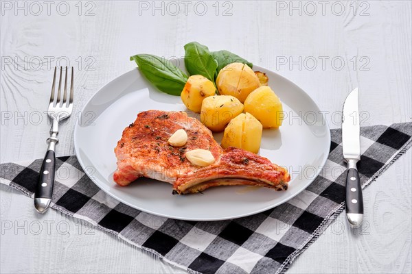 Steak with bone and potato baked in oven in a roasting pan with garlic and thyme