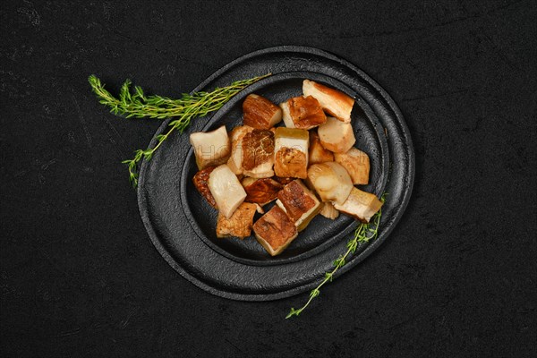 Overhead view of frozen fresh boletus cut on pieces on black stone plate