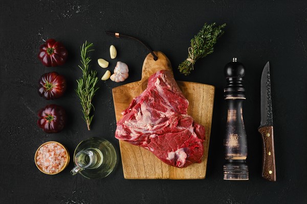 Raw beef top round roast with spices on dark background