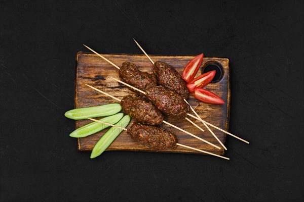 Lamb kebab on skewer on wooden board