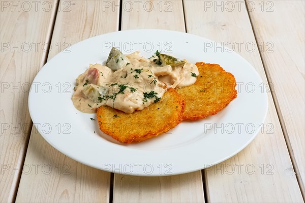 Potato pancakes with flour sauce and pickled cucumber and sausage