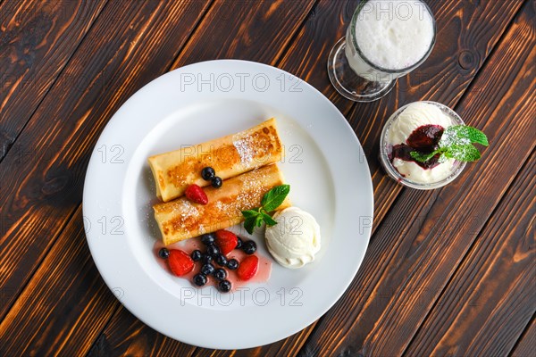 Top view of plate with thin pancakes stuffed with curd and served with berry jam