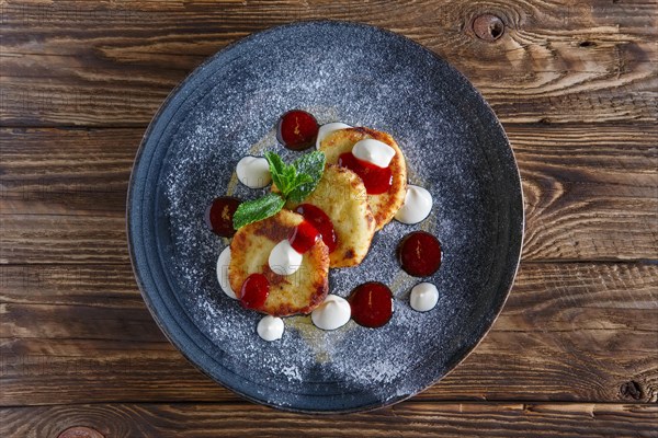 Top view of cheese pancakes served with sour cream and strawberry jam