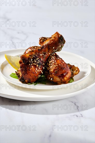Portion of baked chicken legs with spicy sauce on a plate