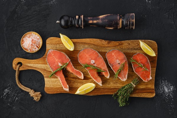 Overhead view of raw trout steaks on wooden cutting board ready for cooking