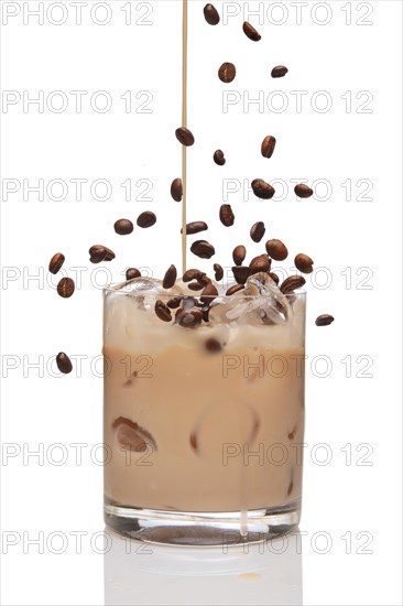 Coffee beans falling into cocktail and Irish creme liqueur pouring in a glass full of ice