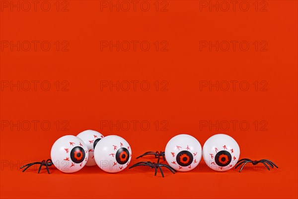 Spooky Halloween eyeballs and spiders on red background with copy space