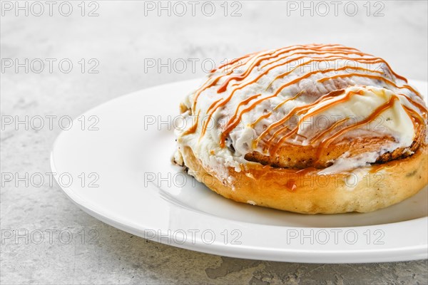 Fresh cinnamon bun with sugar icing and caramel