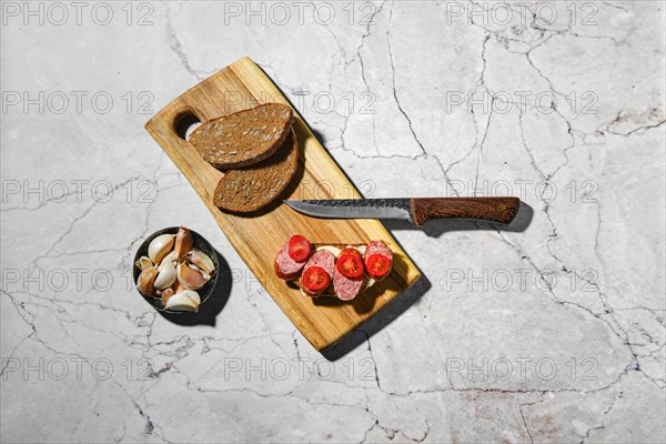 Overhead view of sandwich with smoked pork sausage rings on wooden cutting board on kitchen table