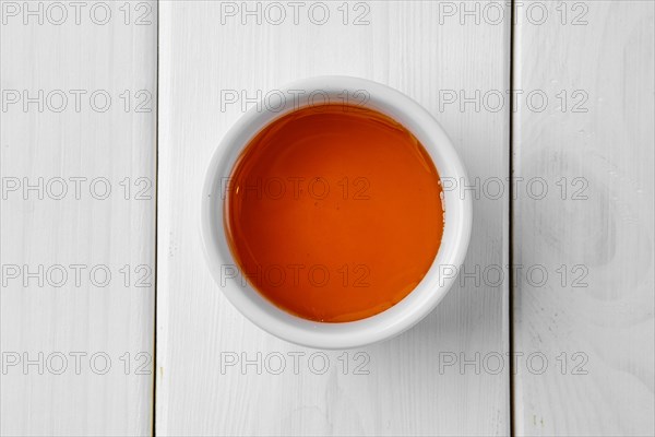 Overhead view of honey in ceramic gravy boat on white wooden table