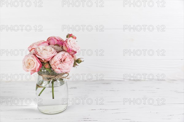 Pink roses flower glass jar white wooden textured backdrop