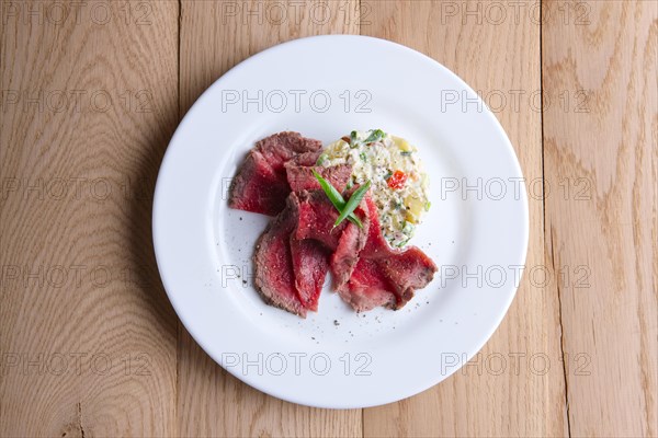 Top view of roasted meat with salad olivier on wooden table