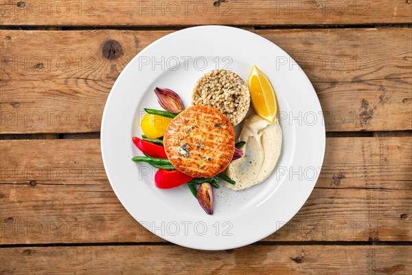 Top view of salmon cutlet with roasted vegetables and green buckwheat