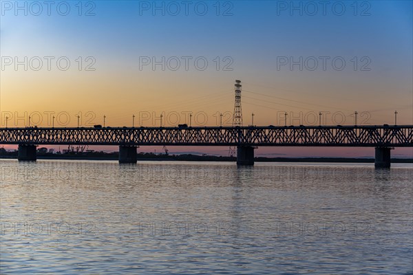 Giant bridge spanning over the Amur river at sunset