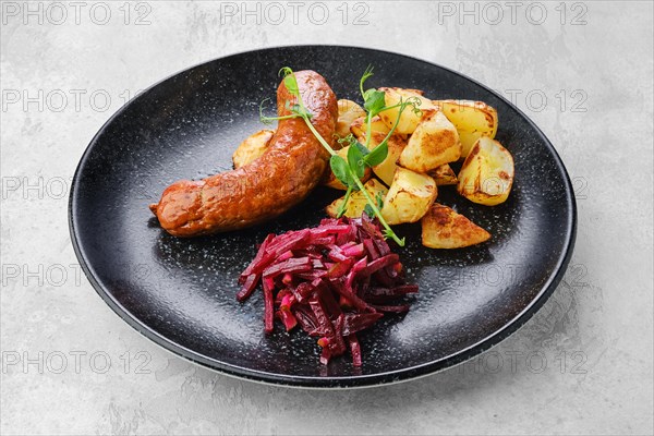 Fried sausage with slices of boiled potatoes fried in oil and marinated beetroot