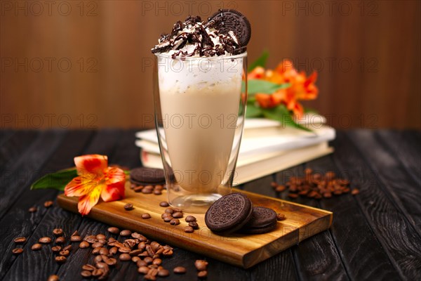 Glass with coffee cocktail with whipped cream and cookie decorated with coffee beans and flowers