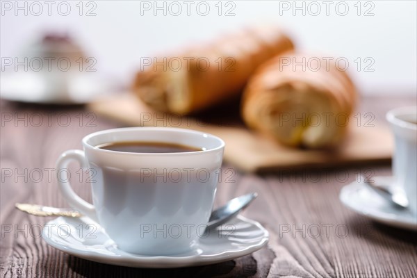 Rolled buns and coffee on wooden table in morning sunlight. Photo with shallow depth of field