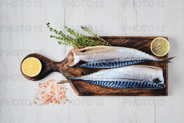 Overhead view of fresh gutted and headless mackerel on wooden cutting board
