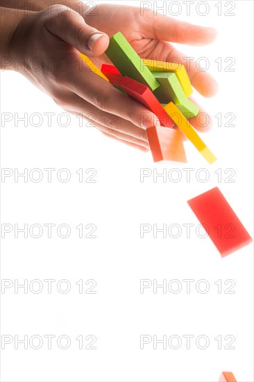 Falling colorful domino off hand on white background