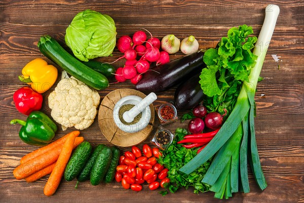 Top view of various fresh vegetables and herbs on dark wooden background