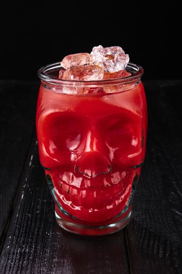 Cocktail bloody Mary in skull cup on dark wooden background