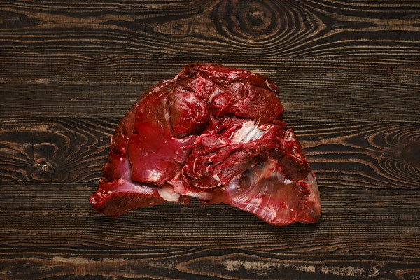 Overhead view of raw deer boneless ham over wooden background