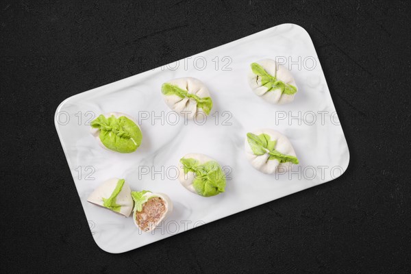 Top view of frozen dumplings stuffed with pork meat and provencal herbs on marble serving plate