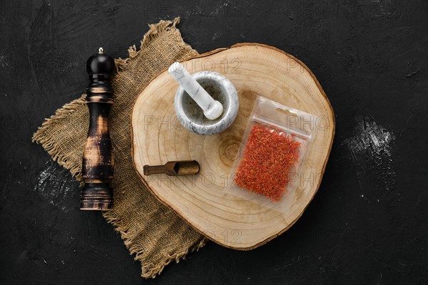 Wooden cross section with saffron in plastic package and stone mortar and mill