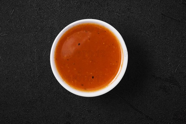 Overhead view of small bowl with spicy orange sauce for poultry
